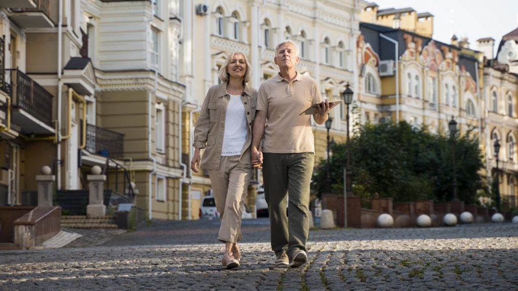 front view elder couple out walk city with tablet
